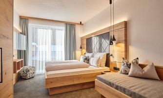 A modern bedroom with two wooden beds. Large windows provide plenty of natural light and a pleasant atmosphere.