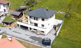 A modern house with a well-maintained garden and a terrace. Surrounded by green spaces and other buildings in a quiet environment.