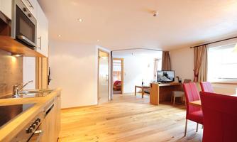 A modern apartment with wooden floors and light walls. The open kitchen and dining area are designed to be inviting.