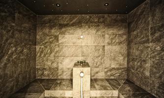 An elegant steam bath with gray natural stone tiles. The ceiling has small light points that simulate a starry sky.