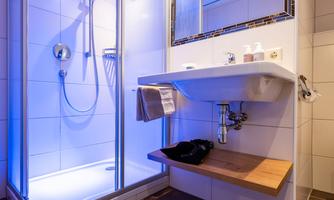 A modern bathroom with a glass shower and stylish tiles. The room is brightly lit and offers a simple, elegant decor.