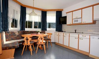 A bright and cozy kitchen with a dining area and modern appliances. The large windows let in a lot of light.