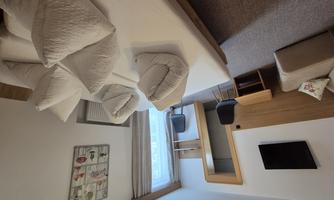 An elegant room with a large bed and many pillows. There is a television and a seating area with a window.