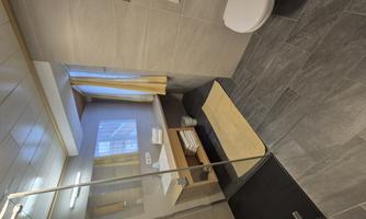 A modern bathroom with a glass shower cabin and a bright color scheme. The space is clean and well-lit, with towels on a shelf.