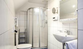 A modern bathroom with shower, sink, and toilet. The walls are brightly tiled, and there is a large mirror.