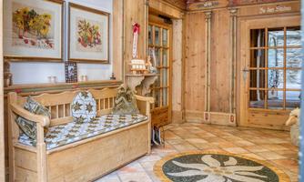 A cozy entrance area with wooden paneling and a decorative floor pattern. A seating area with comfortable pillows invites you to linger.