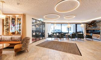 A modern lounge area with comfortable sofas and elegant tables. Large windows provide plenty of light and a welcoming atmosphere.