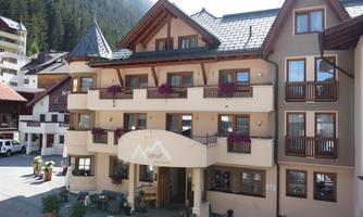 A cozy hotel with multiple floors and balconies. In the foreground are flower boxes that create an inviting atmosphere.