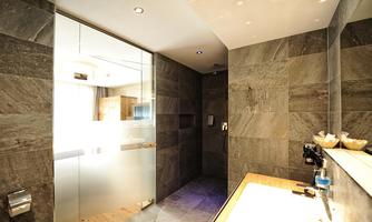 A modern bathroom with gray tiles and a glass shower. The furnishings are minimalist and stylish.