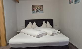 A cozy bedroom with a large bed and comfortable pillows. A decorative picture hangs on the wall, and there are some pictures on the walls.