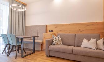 A modern living room with a comfortable couch and a table.  
Large windows provide plenty of daylight and an inviting atmosphere.