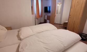 A cozy bedroom with a double bed and bright bed linens. The room features wood details and a television.