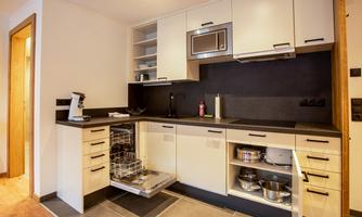 A modern kitchen with light cabinets and a dark countertop. The dishwasher is visible and the furnishings are functional and stylish.