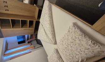 A cozy room with a large bed, white pillows, and modern furniture. A table and a television are also available.