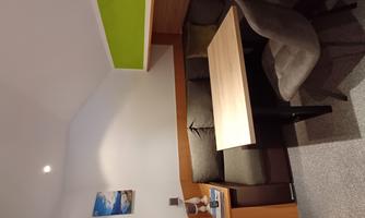 A cozy room with a table and a seating area. The walls are bright and one corner is painted green.