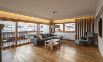 A modern living room with a cozy sofa and an armchair. Large windows provide plenty of daylight and a beautiful view outside.