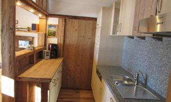 A modern kitchen with wooden shelves and a granite countertop. The decor is bright and inviting.