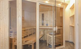 A modern sauna with wood paneling and glass doors. The room is bright and invitingly designed.