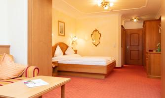 A cozy hotel room with a double bed and a small table. Warm colors and an inviting atmosphere create a pleasant ambiance.