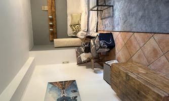 A cozy living space with a white sofa and a wooden crate. A painting of a mountain landscape hangs on the wall.