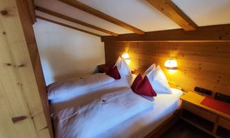 A cozy bedroom with wooden paneling and two beds. The lighting creates a warm atmosphere.