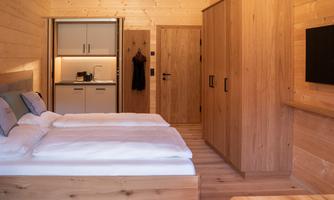 A cozy room with wood paneling and a double bed. The kitchen is well-equipped and there is a desk as well as a television.