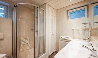 A modern bathroom with a shower cubicle and a bathtub. Bright tiles and windows create a pleasant atmosphere.