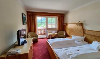 A cozy hotel room with two beds and beautiful wooden furniture. The window offers a view of the surrounding landscape.