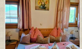 A cozy room with a bed for four people. There is a private bathroom and a friendly decor.