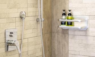 A modern shower with ceramic tiles and a hand shower. On the wall, there are shampoo and shower gel bottles in a practical holder.