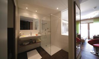 A modern bathroom with a glass shower and a bright sink. The walls are in neutral colors and there is plenty of natural light.