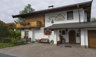 A beautiful house in alpine style with a flower balcony and a well-maintained garden. The facade is light with an inviting front door.