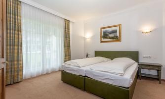 A cozy bedroom with a double bed and a table. Large windows let in plenty of light and offer a view outside.
