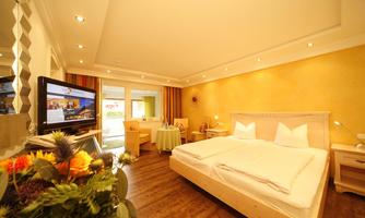 A cozy hotel room with a large bed and modern furniture. There is a television and a small table with chairs.