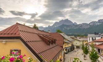 A picturesque village with colorful buildings and roofs made of tiles. In the background, majestic mountains rise under a cloudy sky.