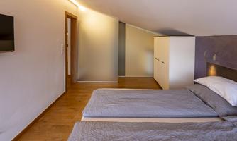 A modern bedroom with two beds and a wardrobe. The room has wooden floors and a cozy atmosphere.