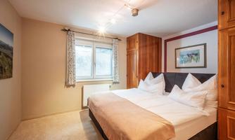 A bright bedroom with two single beds and friendly decor. Large windows provide plenty of daylight and a cozy atmosphere.