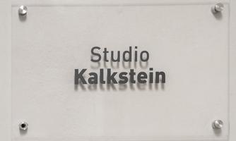 A transparent sign with the inscription "Studio Kalkstein". It is simply and modernly designed.