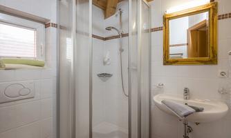 A modern bathroom with a glass shower and a sink. A hinted mirror in a golden frame complements the elegant design.