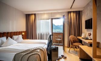 A modern hotel room with a double bed and a balcony. The decor is cozy and offers a beautiful view of the mountains.