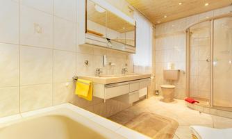 A modern bathroom with a bathtub and a walk-in shower. Bright tiles and practical mirrors give the room an inviting ambiance.