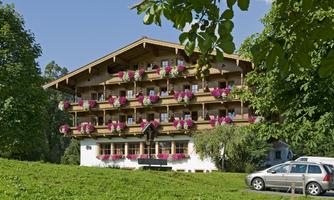 A picturesque mountain hotel with blooming balconies, surrounded by green landscape. The sunny facade invites you to linger.