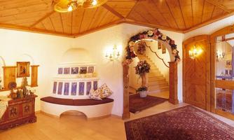 An inviting entrance area with wooden floorboards and a decorative rug. Pictures hang on the walls, and a curved staircase leads upwards.