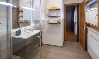 A modern bathroom with a glass shower enclosure and a sink. Bright and inviting with towel racks and natural wood elements.