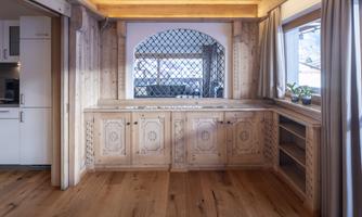 A bright room with wooden walls and a large window. A wooden dresser and wooden floor give the room a warm atmosphere.