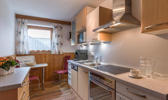 A modern kitchen with light wooden cabinets and a pleasant atmosphere. There is a table with chairs and a kitchenette with various appliances.