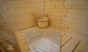 A relaxing sauna area with wooden paneling. Towels and a ladle are ready.