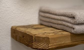 A wooden shelf with neatly folded towels. The calm atmosphere conveys coziness and cleanliness.