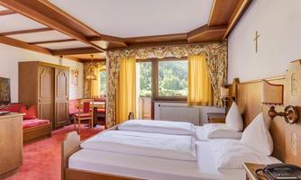 A cozy hotel room with two single beds and a beautiful view outside. The decor is rustic and inviting, with warm colors and wooden details.