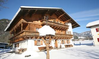 A beautiful, wooden-clad chalet in the snow. Surrounded by a winter landscape and clear, blue sky.